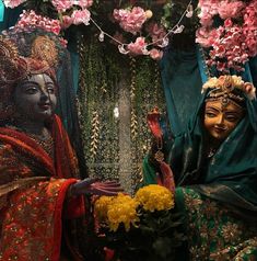 two women dressed in colorful costumes and holding flowers