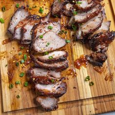 sliced pork on a cutting board with green onions and seasoning sprinkles