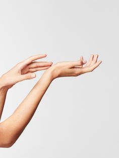 two hands reaching out towards each other to catch something in the air on a white background