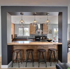 an open concept kitchen with bar stools in the center and wood accents on the walls