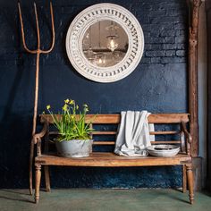 a wooden bench sitting in front of a blue wall with a mirror on the wall