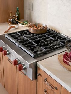 a stove top oven sitting inside of a kitchen next to wooden cabinets and counter tops