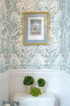 a white toilet sitting in a bathroom next to a painting on the wall above it