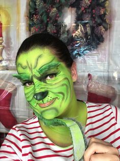 a person with green face paint on their face and wearing a red and white striped shirt