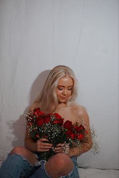 a woman is sitting on the floor with roses in her lap and holding flowers behind her back