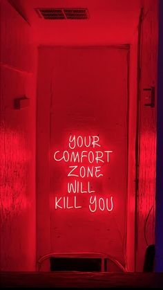 a red room with graffiti written on the door and in front of it is a neon sign that says your comfort zone will kill you