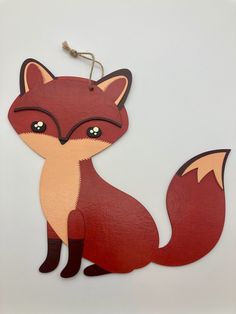 a wooden cutout of a red fox sitting on top of a white table next to a string