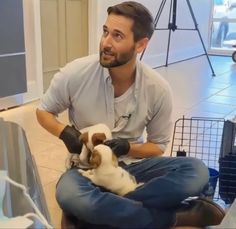 a man sitting on the floor holding two kittens