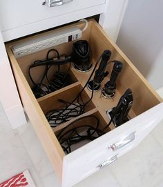 an open drawer with many different electrical cords and plugs in it on the floor