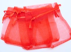 an orange piece of sheer fabric on a white tablecloth with red ribbon tied around it