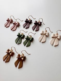 six pairs of earrings with bows hanging from them on a white surface, all in different colors