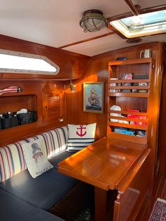 the interior of a sailboat with wooden walls and wood trimmings, along with an l - shaped couch