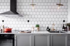 a kitchen with grey cabinets and white subway tiles on the wall, along with an oven