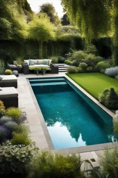 an outdoor swimming pool surrounded by greenery and shrubs, with lounge chairs around it