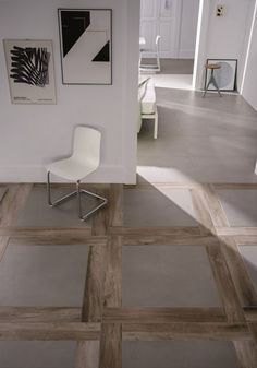 a white chair sitting in the middle of a room next to a wall with pictures on it