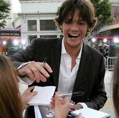 a man in a suit signing autographs for people