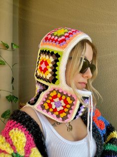 a woman wearing a multicolored crocheted hat and scarf, with sunglasses on her head