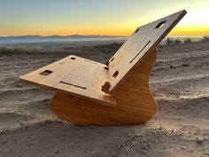 a wooden bench sitting on top of a sandy beach next to the ocean at sunset