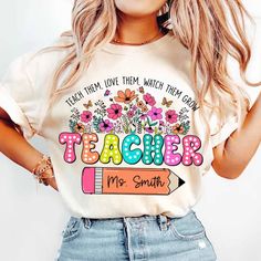 a woman wearing a teacher shirt with flowers on it