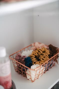 a metal basket filled with lots of different types of hair clips on top of a white counter