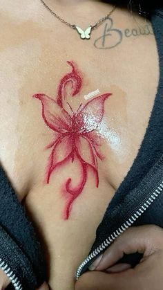 a woman's chest with a red flower tattoo on her left side and the words beauty written across it