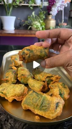 someone is holding up some food on a plate in front of a table with flowers