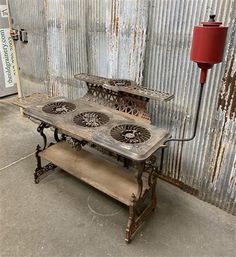 an old metal table with three fans on it and a red lamp in the background