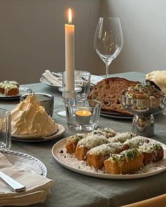 a table topped with plates filled with food next to a candle and wine glass on top of a table