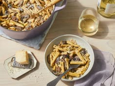 two bowls filled with pasta next to wine glasses