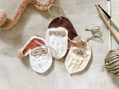 three handmade santa claus ornaments next to yarn and crochet