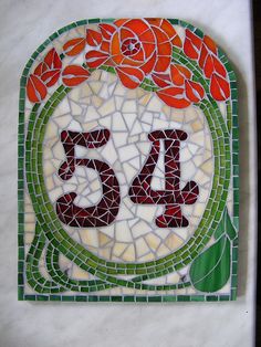 the number twenty five is made out of glass and has red flowers on it's side