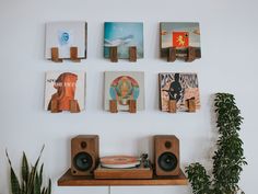 some wooden speakers are on top of a shelf next to books and pictures hanging on the wall