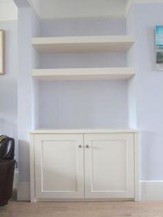 a living room with white shelves and leather chair