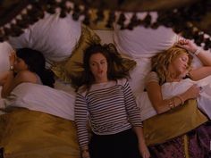 three women laying in bed with white pillows