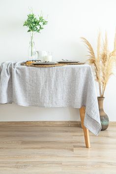 a table with a white cloth on it next to a potted plant and vase