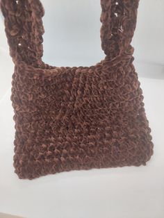 a crocheted brown bag sitting on top of a white table next to a wall