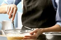 a person in an apron is mixing something in a bowl