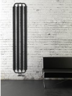 a white brick wall next to a black bench and a radiator on the wall