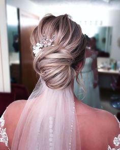 the back of a bride's head wearing a veil and flowers in her hair