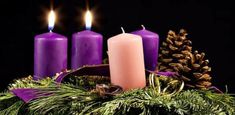 three lit candles sitting on top of a table next to pine cones and evergreen branches