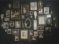 an assortment of framed and unframeed pictures are arranged on the wall in this dark room