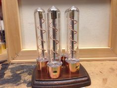 three glass tubes sitting on top of a wooden stand