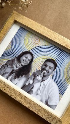 a wooden frame with an image of two people and a cat in the center, on top of a brown surface