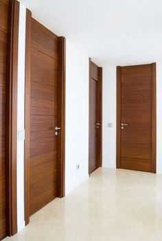 three wooden doors in an empty room with white walls and flooring on either side