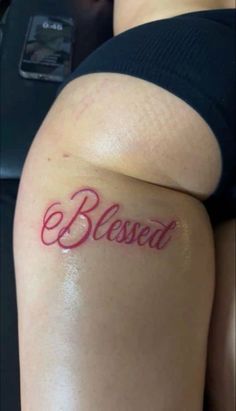 a woman with a tattoo on her thigh that says,'blessed'in red ink