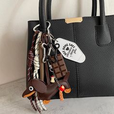 a black purse with key chains hanging from it's side and a bag tag attached to the handle