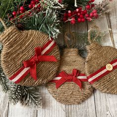 three burlap christmas ornaments with red bows on them and pine branches in the background