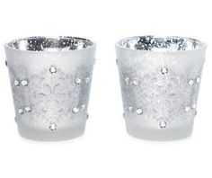 two silver glass vases sitting next to each other on a white surface with snowflakes all over them