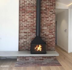 a brick wall with a wood burning stove in the center and wooden floors on both sides