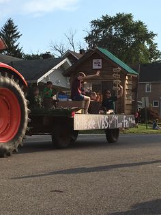 people are riding in the back of a tractor with a sign on it's flat bed